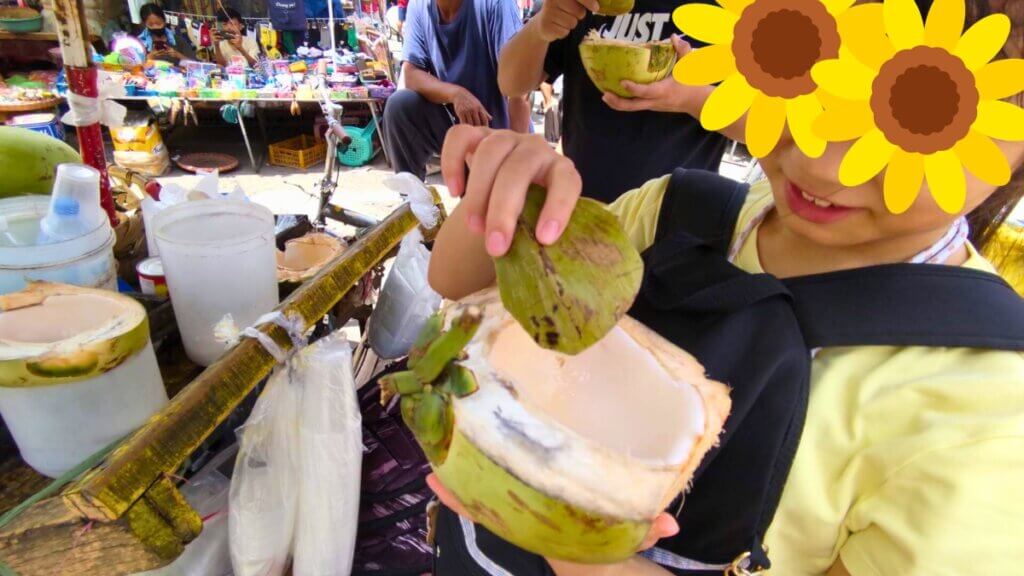 フィリピン、セブ島のカルボンマーケットでココナッツを食べる娘